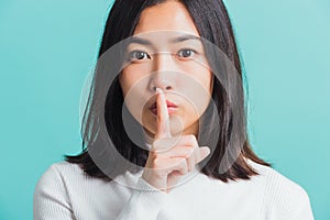 Woman holding index finger on her mouth lips
