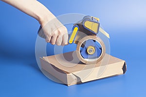 Woman holding an industrial tape dispenser,cardboard box sealing