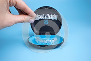 Woman holding invisalign transparent retainers with a box on the table, flatlay top view. Selective focus photo