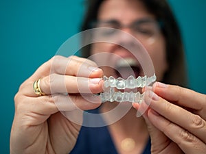 WOMAN HOLDING AN INVISALING BRACE ON A GREEN BACKGROUND photo