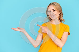 Woman holding invisible product on hand, pointing with finger at object