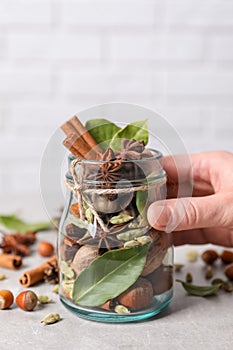 Woman holding jar with aromatic potpourri on white table, closeup