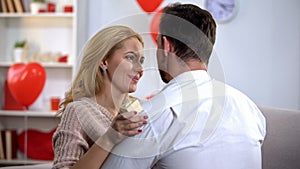 Woman holding jewelry gift box and hugging man, looking at boyfriend with love