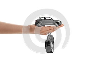 Woman holding key and automobile model on white background, closeup. Car buying