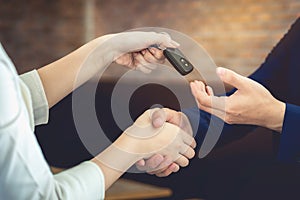 The woman holding the key of the car has agreed to give the customer.