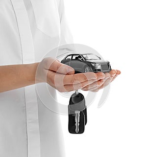 Woman holding key and miniature automobile model on background, closeup. Car buying