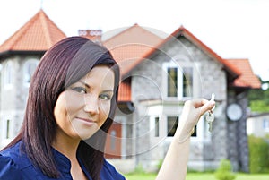Woman holding keys with house background