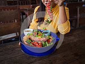 Woman holding king crabs Alaska leg with wooden table and chairs