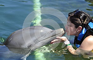 Woman holding a kiss from a dolphin.