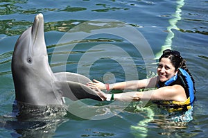 Woman holding a kiss from a dolphin.