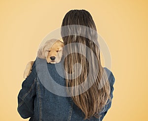 Woman holding labrador puppy on her shoulder