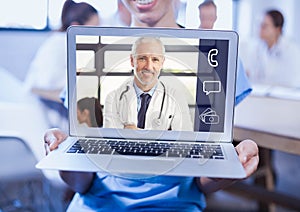 Woman holding a laptop with doctor on video call screen