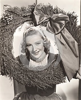 Woman holding large Christmas wreath with bow