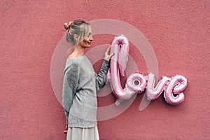 Woman is holding large inflatable letters LOVE.