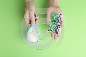 Woman holding laundry capsules and detergent powder on green background, top view