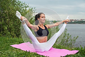 Woman holding legs apart doing exercises aerobics warming up with gymnastics for flexibility leg stretching workout