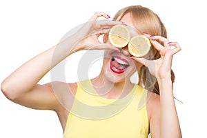 Woman holding lemon near her eyes.