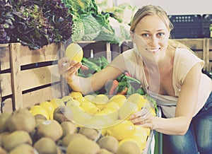 Woman holding lemons in hands in fruit store