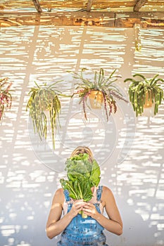 Woman holding lettuce in her garden. Sustainable agriculture and healthy lifestyle concept.