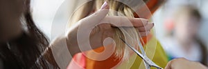 Woman holding lock of hair and cutting with scissors equipment