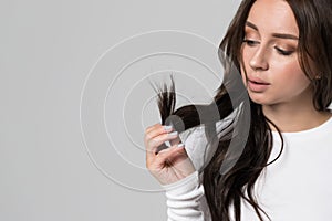 Woman holding and looking at split ends of her damaged long hair. Separated dry ends, hair care problem