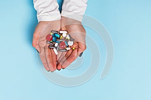 Woman holding a lot of different tablets and pills in her hands