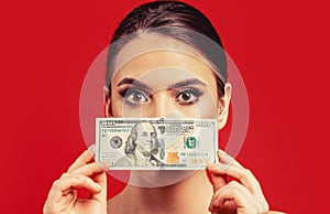 Woman holding lots of money in dollar currency. Woman with dollars in hand. Portrait of a young girl covering her face