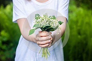 Woman holding a bouquet of lilly of valley flowers