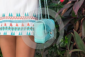 Woman holding luxury snakeskin python handbag. Bali island. Fashion bag concept on a tropical island.