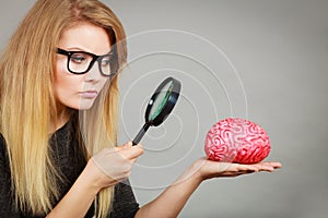 Woman holding magnifying glass investigating brain