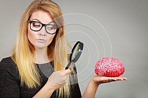 Woman holding magnifying glass investigating brain photo
