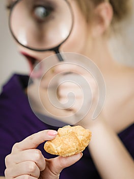 Woman holding magnifying glass investigating bread