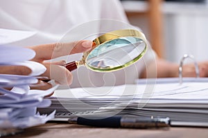 Woman Holding Magnifying Glass Over Invoice