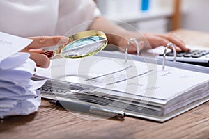 Woman Holding Magnifying Glass Over Invoice