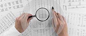 Woman holding a magnifying glass pointing at numbers on financial documents. ?oncept of finance, search and accounting