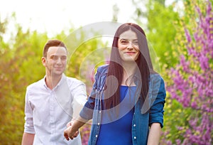 Woman holding man`s hand and leading him on nature outdoor