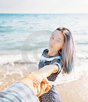 Woman holding man`s hand and leading him to sea.