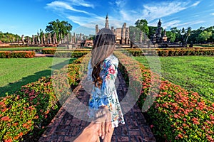 Woman holding man`s hand and leading him to Wat Mahathat Temple in the precinct of Sukhothai Historical Park