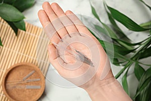 Woman holding many acupuncture needles over table, top view