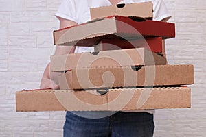 Woman holding many stacked in disorder carton pizza boxes of different sizes, restaurant delivery concept