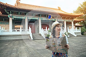 Woman holding a map and visiting old temple