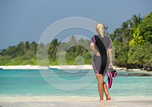 Woman holding mask and flippers for swimming on tropical beach