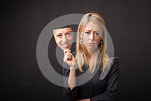 Woman holding mask of her happy face photo