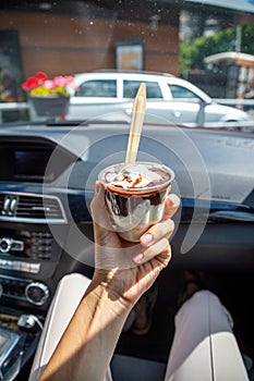 Woman holding the McDonalds McFlurry Ice Cream with chocolate in a car after drive thru. Drive thru concept