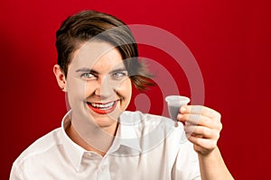 Woman holding a menstrual cup over red background