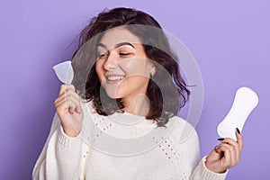 Woman holding menstrual cup and sanitary pad in hands. Feminine hygiene alternative product instead of tampon during her period.