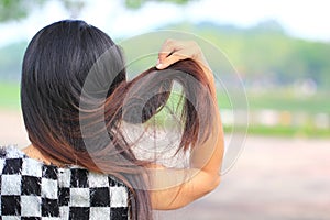 Woman holding messy damaged dry hair in hands on nature background, Haircare concept