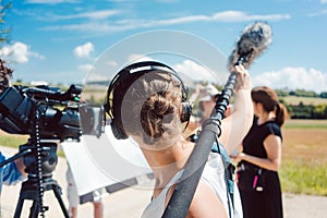 Woman holding microphone on a boom during video production