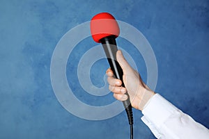 Woman holding microphone on color background