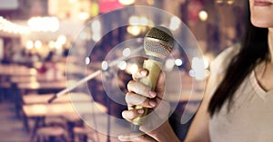 Woman holding microphone in hand on pub and restaurant